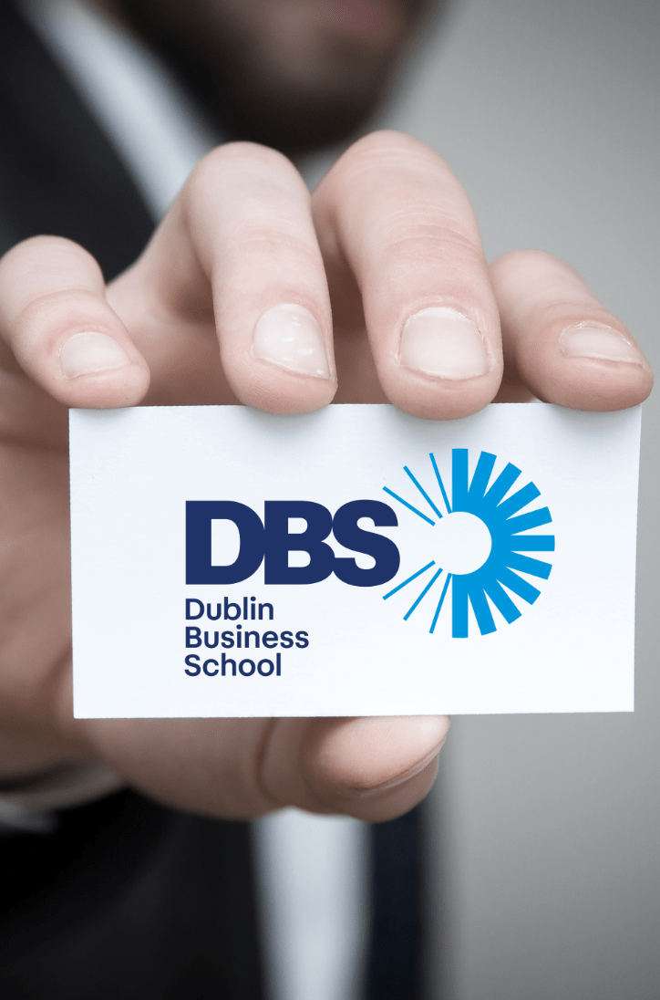 Hand holding out a business card that has DBS Dublin Business School printed on it
